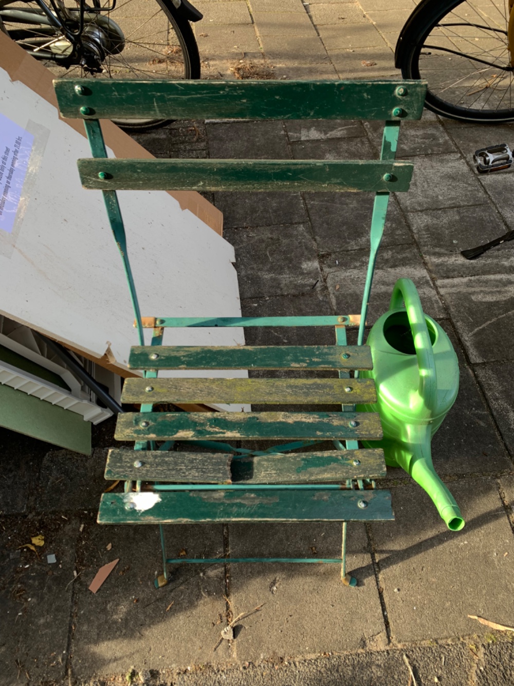 Green garden chair with one plank broken and a watering can photo 2